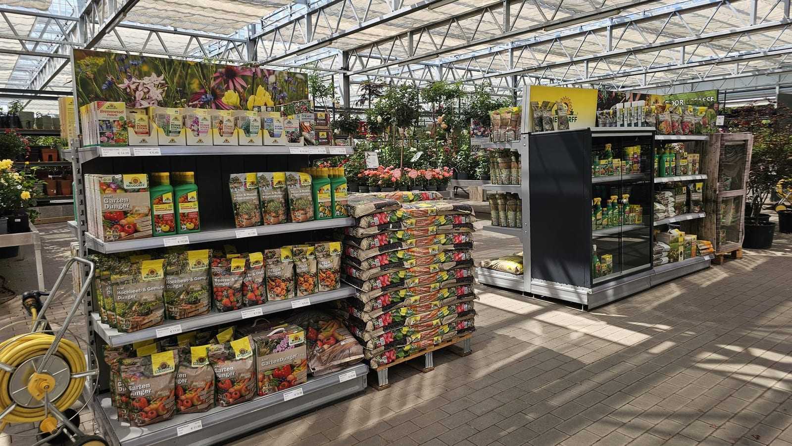 Regal mit Gartendünger, daneben Erdsäcke auf einer Palette